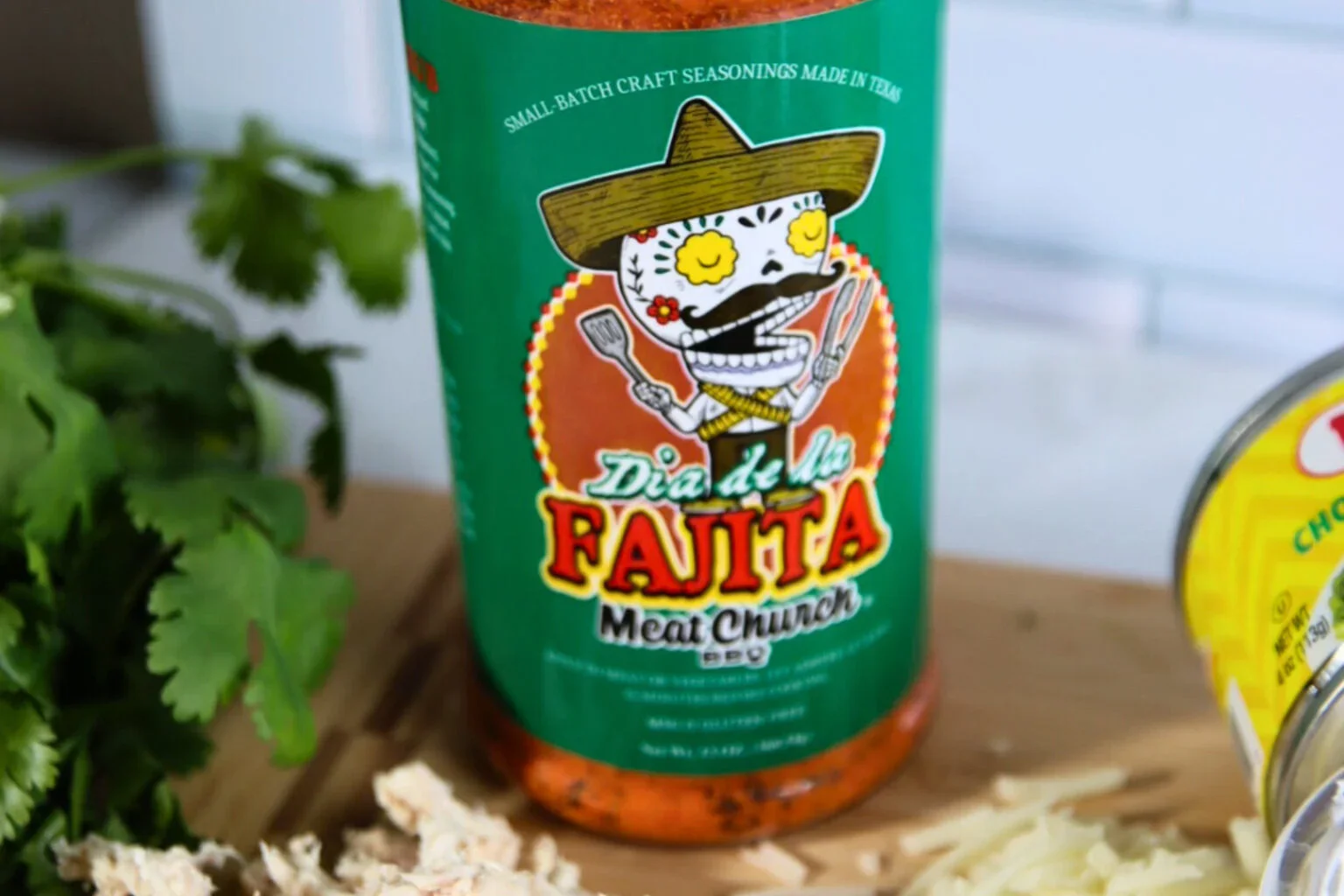 2025-04-26-18.01.36-1-1536x1024.webp Meat Church Dia de la Fajita seasoning beside cilantro, shredded chicken, and cheese.