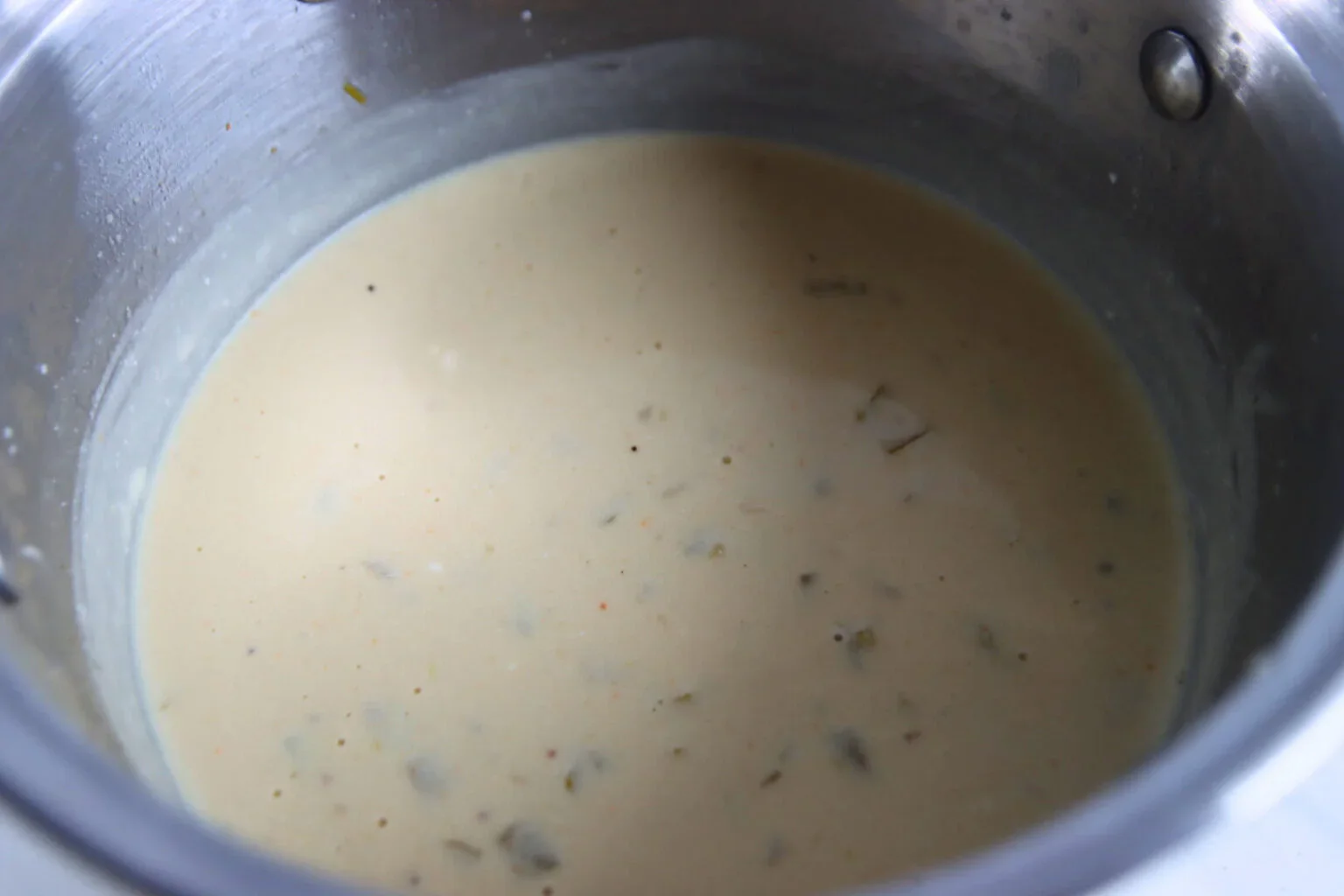2025-04-26-18.01.37-1536x1024.webp Creamy white enchilada sauce with green chiles simmering in a saucepan.
